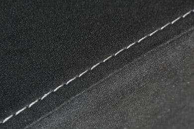 Weiße Nähte auf schwarzem Stoff