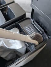 Blick in die MOVA Z50 Ultra Station mit Reinigungsbürste im Staubsaugerbeutel-Fach, zeigt durchdachte Aufbewahrungslösung für Wartungszubehör